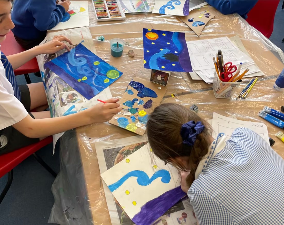 Children painting starry night scenes around a table