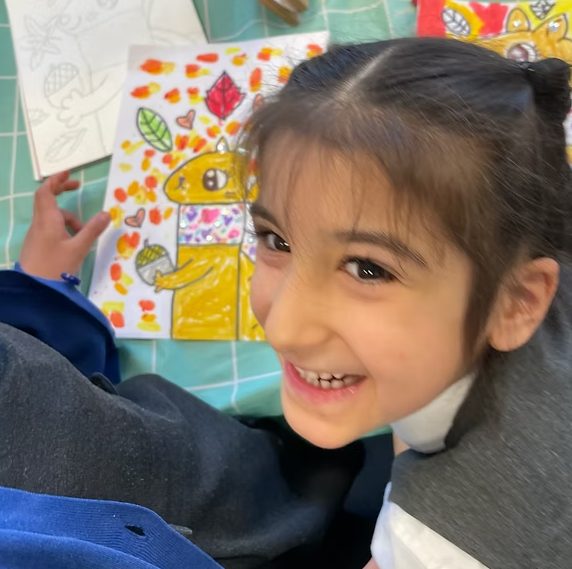 Smiling pupil with her autumn artwork